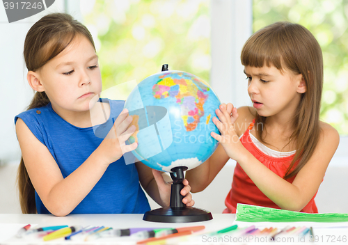 Image of Little girls are examining globe