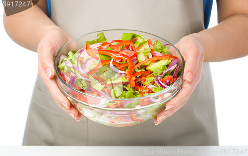 Image of Cook is holding a big bowl with fresh salad