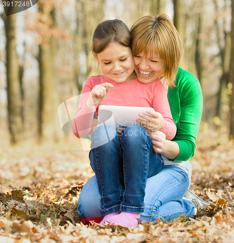 Image of Mother and her daughter is playing with tablet