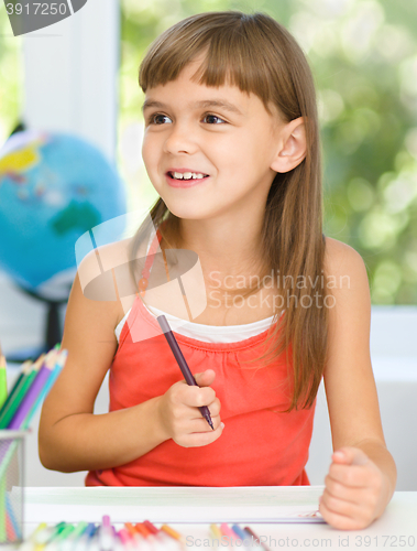 Image of Little girl is drawing using pencils