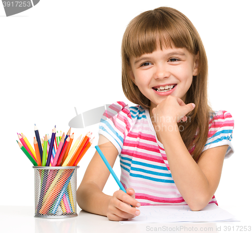 Image of Little girl is drawing using pencils