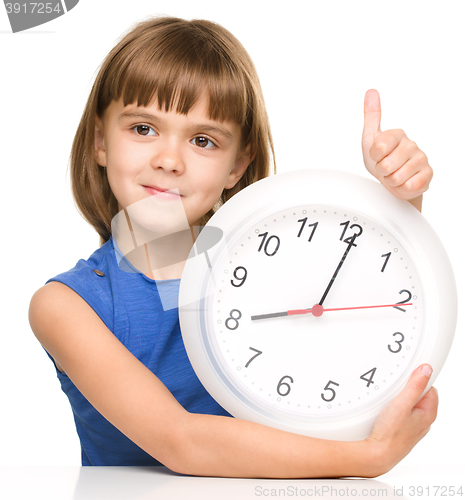 Image of Little girl is holding big clock