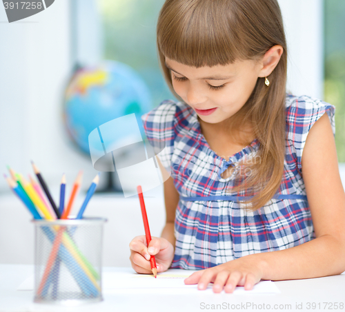 Image of Little girl is drawing using pencils