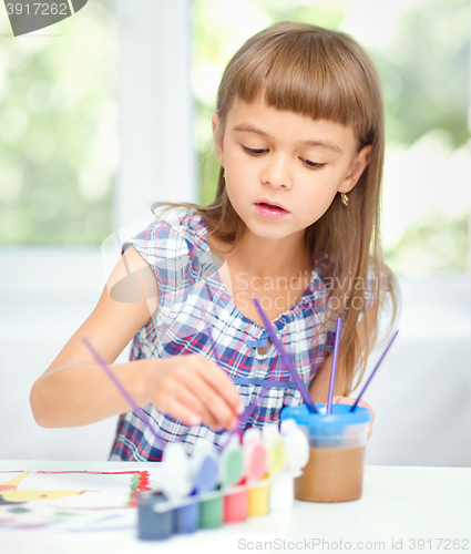 Image of Little girl is painting with gouache