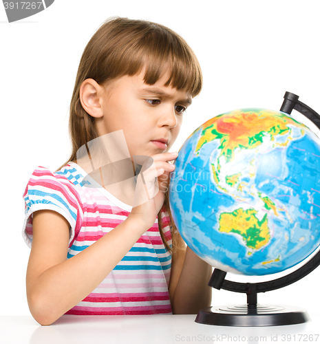 Image of Little girl is examining globe