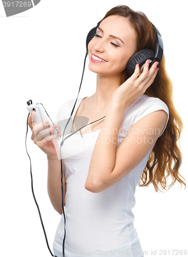 Image of Young woman enjoying music using headphones