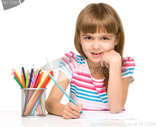 Image of Little girl is drawing using pencils