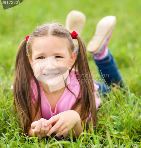 Image of Portrait of a little girl laying on green grass