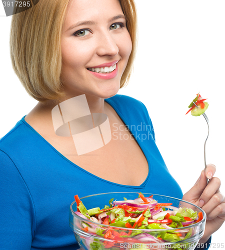 Image of Young attractive woman is eating salad using fork