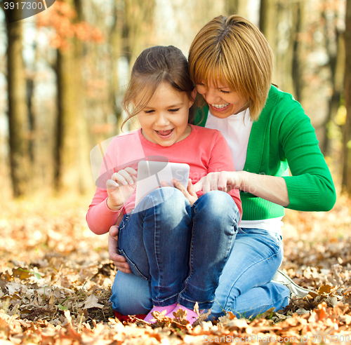 Image of Mother is reading from tablet with her daughter