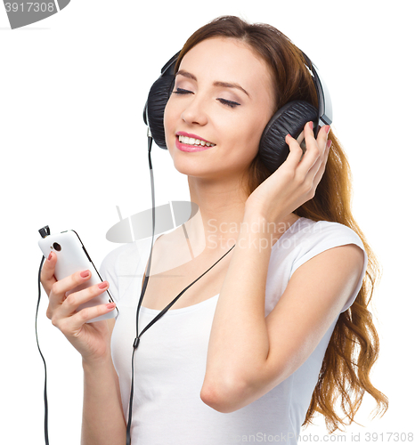 Image of Young woman enjoying music using headphones