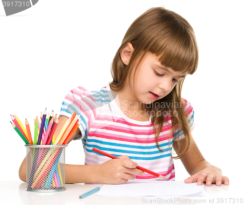 Image of Little girl is drawing using pencils