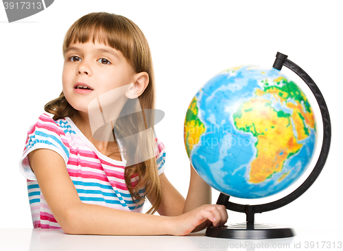 Image of Little girl is examining globe