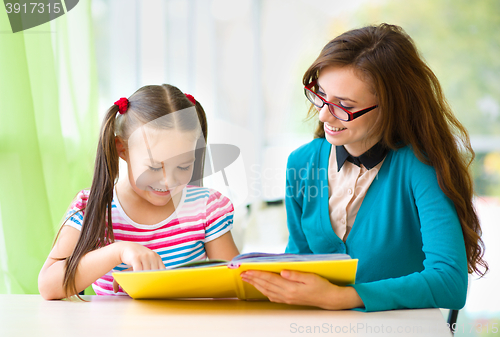 Image of Mother is reading book with her daughter