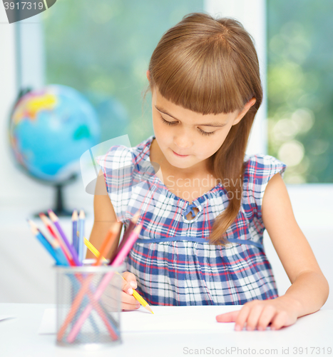 Image of Little girl is drawing using pencils