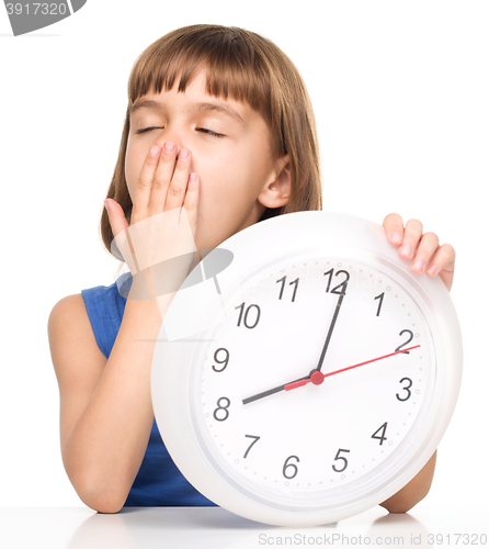 Image of Little girl is holding big clock