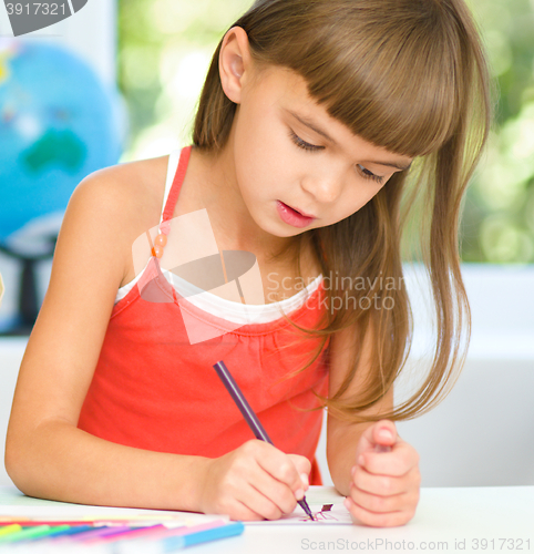 Image of Little girl is drawing using pencils