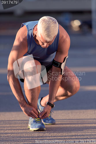 Image of Man tying running shoes laces