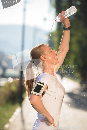 Image of woman drinking  water after  jogging