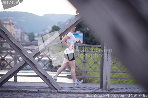 Image of sporty woman running  on sidewalk