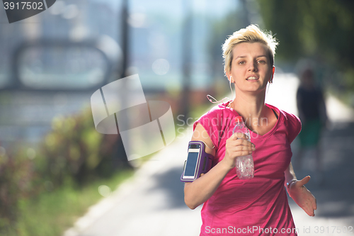 Image of sporty woman running  on sidewalk