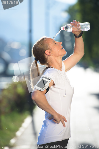 Image of woman drinking  water after  jogging