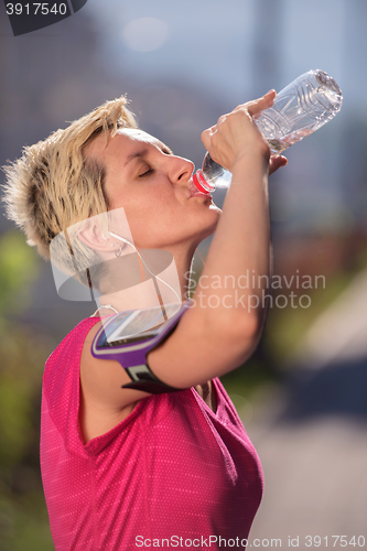 Image of woman drinking  water after  jogging