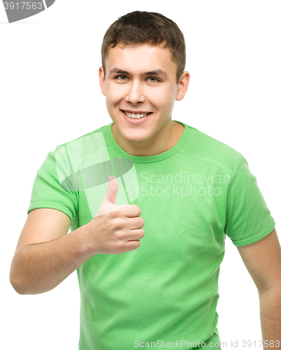 Image of Cheerful young man showing thumb up sign
