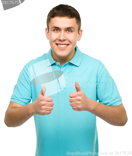 Image of Cheerful young man showing thumb up sign