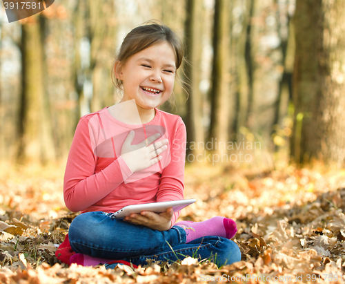 Image of Little girl is reading a book outdoors