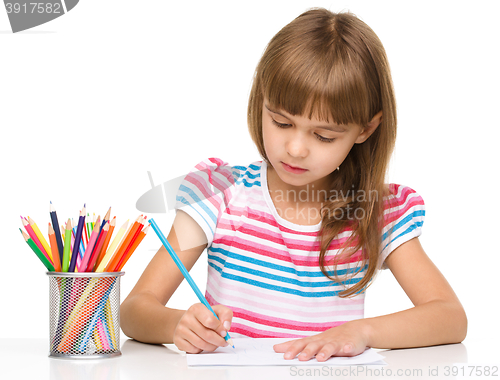 Image of Little girl is drawing using pencils