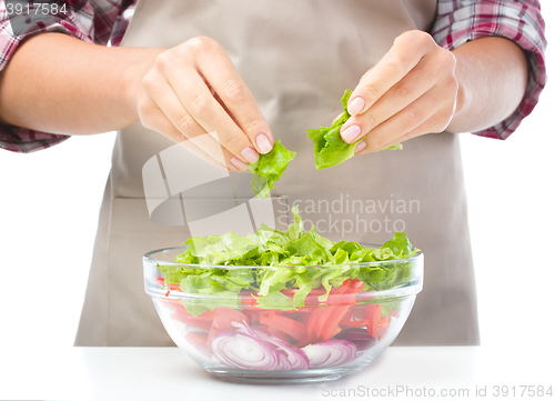 Image of Cook is tearing lettuce while making salad