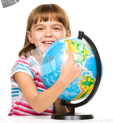 Image of Little girl is examining globe