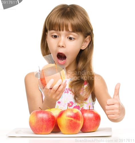 Image of Little girl with apples is showing thumb up sign