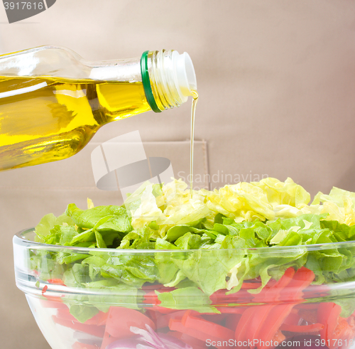 Image of Cook is pouring olive oil into salad