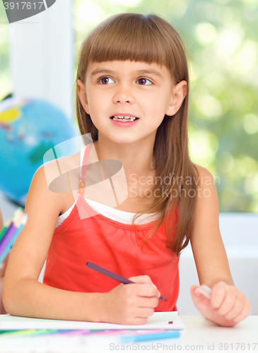Image of Little girl is drawing using pencils