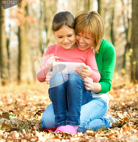 Image of Mother and her daughter is playing with tablet
