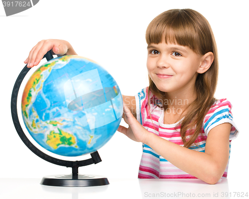 Image of Little girl is examining globe