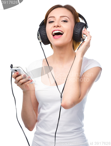 Image of Young woman enjoying music using headphones