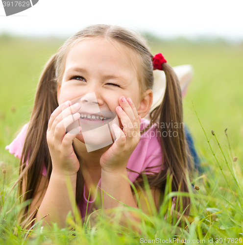 Image of Portrait of a little girl laying on green grass
