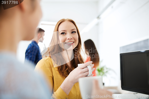 Image of happy creative team drinking coffee at office