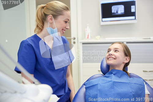 Image of happy female dentist with patient girl at clinic