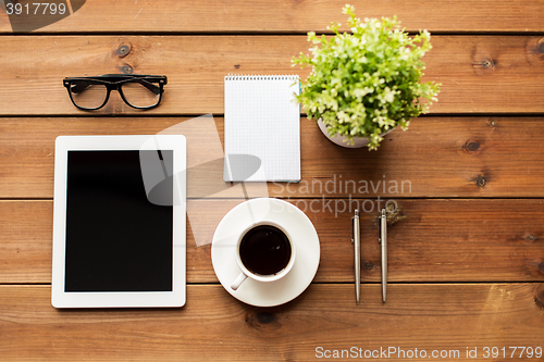 Image of close up of tablet pc, coffee, glasses and notepad