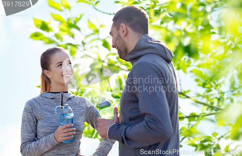 Image of smiling couple with bottles of water outdoors