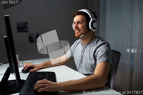 Image of man in headset playing computer video game at home