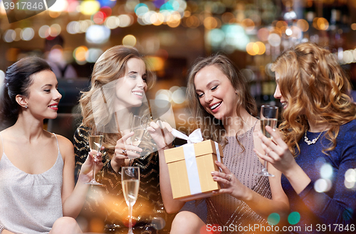 Image of happy women with champagne and gift at night club