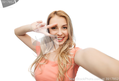 Image of smiling woman taking selfie and showing peace sign