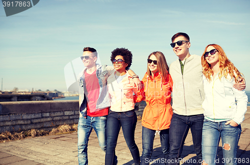 Image of happy teenage friends walking along city street