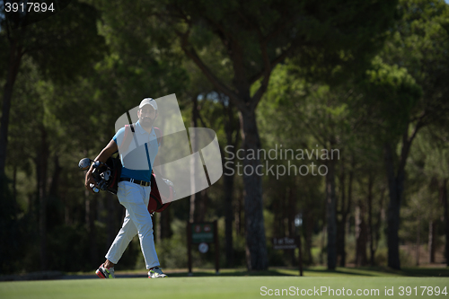 Image of golf player walking and carrying bag