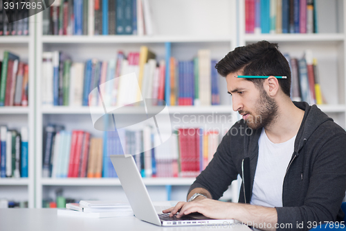 Image of student in school library using laptop for research